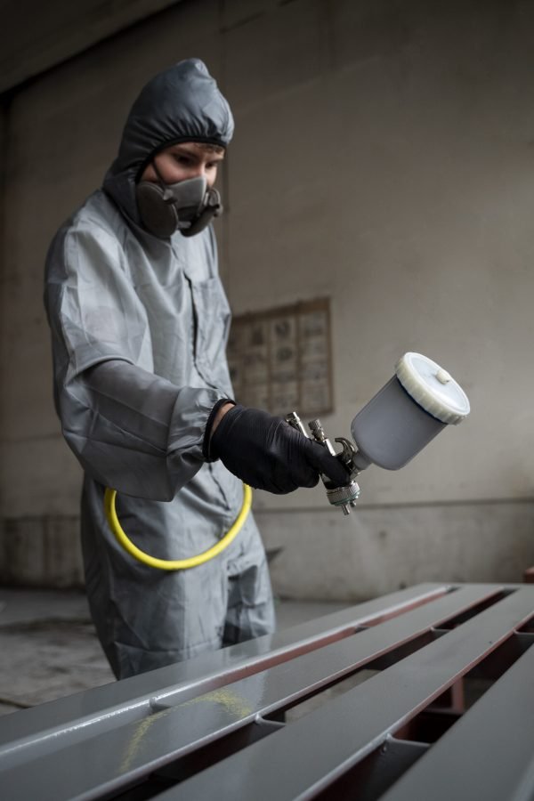 side-view-man-spraying-powder-paint-from-gun